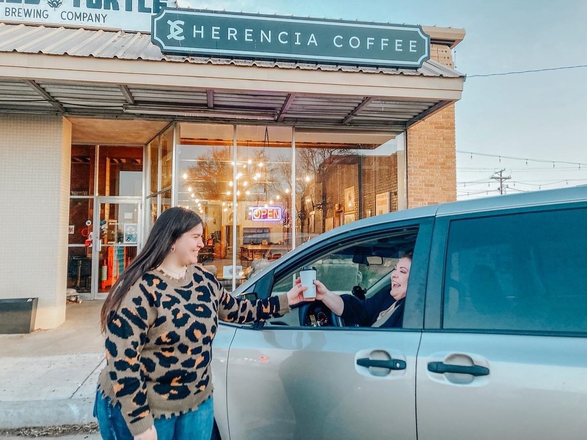 barista delivering coffee curbside outside of Herencia Coffee